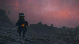 Sam traversant une région rocheuse avec un dos plein de cargo. Il pleut et le ciel est rougeâtre et menaçant.