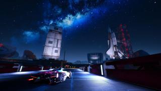 Un bolide traverse une route de nuit entre une tour de contrôle et une navette spatiale, qui semble prête à partir.
