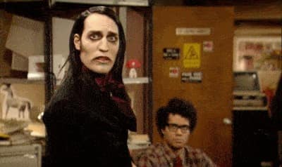 Richmond de la série IT Crowd regarde la caméra dramatiquement pendant que ses collègues tentent de comprendre ce qu'il regarde.