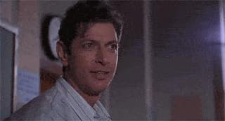 Jeff Goldblum esquisse un sourire et lance un regard vers son côté avec un air satisfait.