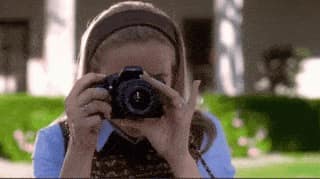 Alicia Silverstone du film Clueless en train de prendre un cliché avec un appareil photo.